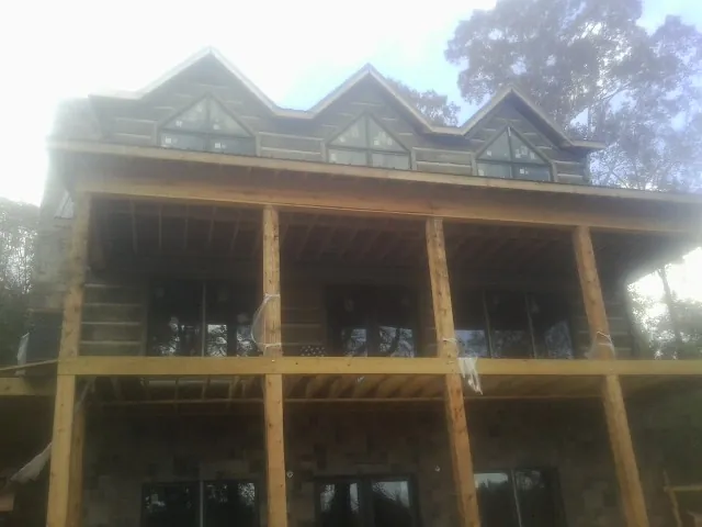 Dormers and porch framing on a large log home under construction — Roof Coating work by our crew in Ferrum