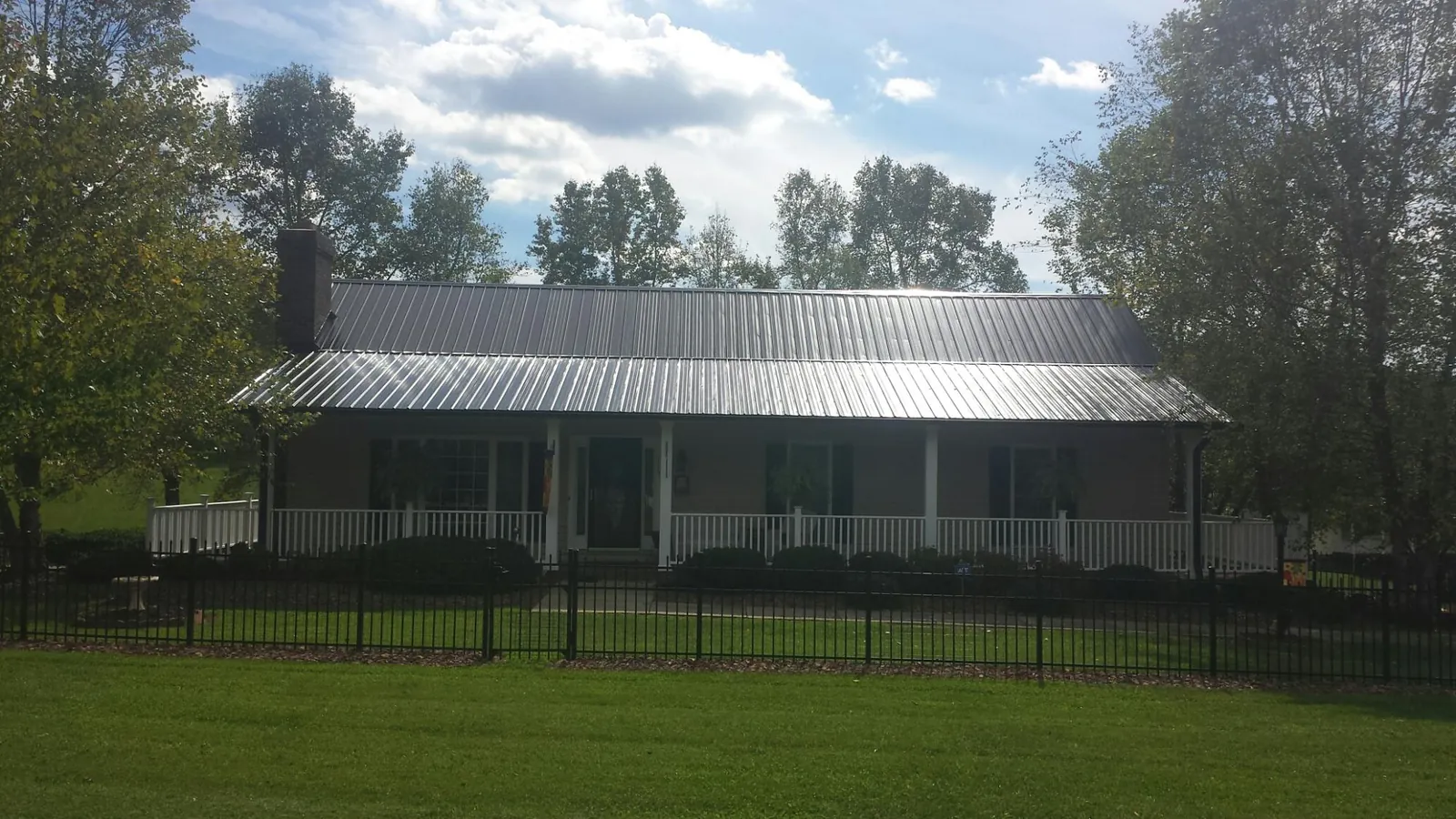 Gray metal roof on a brick ranch with a full width front porch — Gutter Guard Installation work by our crew in Ferrum